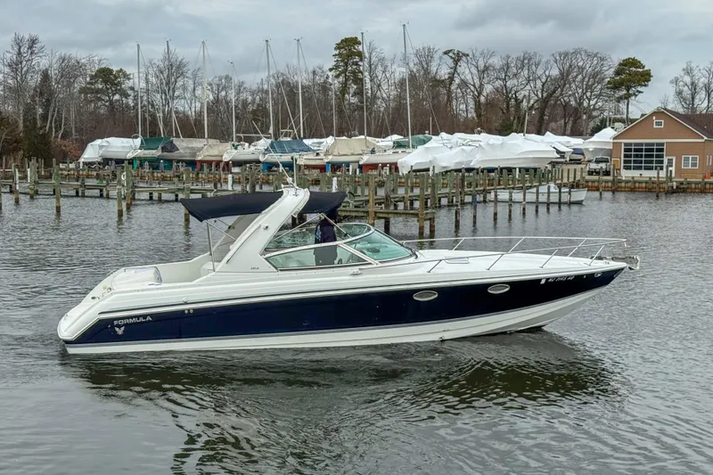Slide: The Image of 2004 Formula 330 Sun Sport boat cruising near a marina with docked vessels. - 4