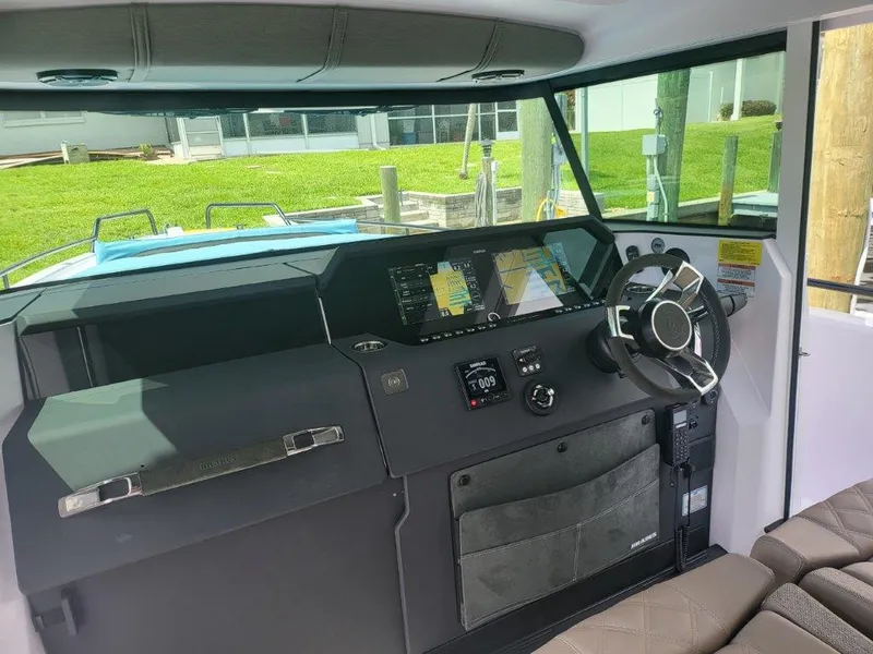 Slide: The Image of 2024 Axopar 37 XC CROSS CABIN helm with modern navigation displays and steering wheel. - 13