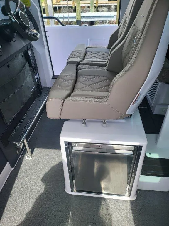 Slide: The Image of 2024 Axopar 37 XC CROSS CABIN interior with cushioned seats and storage compartment. - 16