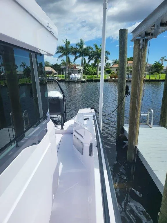 Slide: The Image of 2024 Axopar 37 XC CROSS CABIN docked by a scenic waterfront. - 17