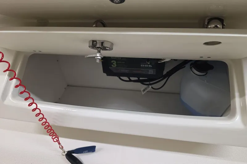 Slide: The Image of Storage compartment of 2026 Sailfish 272 CC boat with battery and coiled safety cord. - 10