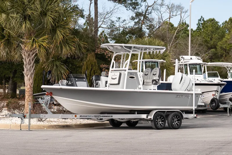 Slide: The Image of 2025 Sea Pro 230 Bay boat on trailer, parked near palm trees. - 2