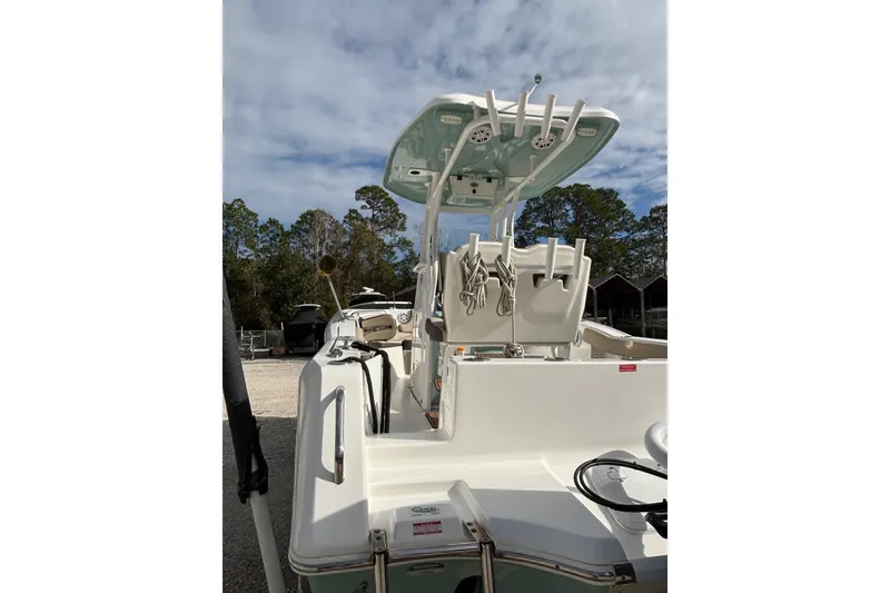 Slide: The Image of 2021 Tidewater 232 CC Adventure boat with T-top and rod holders, parked outdoors. - 4