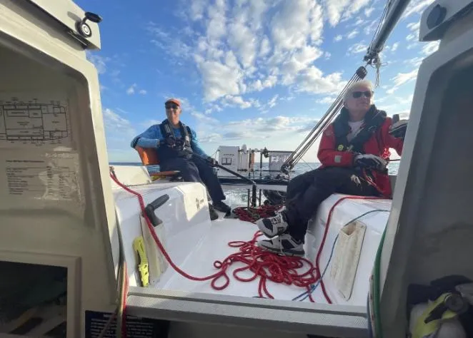 Slide: The Image of Two people sailing on a 2022 Corsair 880 Sport under a clear blue sky. - 13