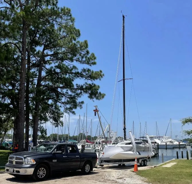 Slide: The Image of Truck towing 2022 Corsair 880 Sport sailboat near marina with trees and blue sky. - 19