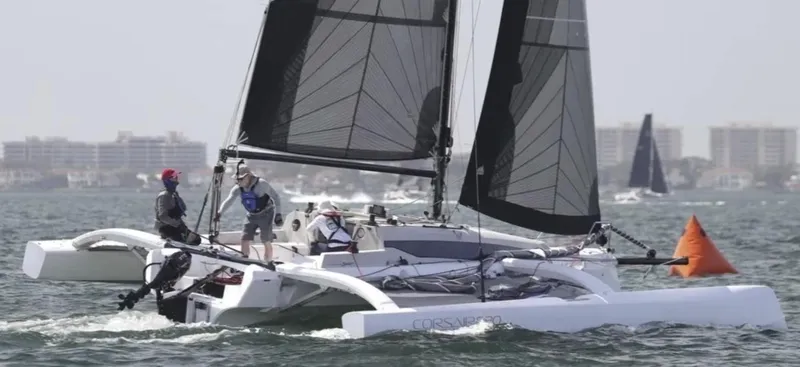 Slide: The Image of 2022 Corsair 880 Sport trimaran sailing on open water with crew onboard. - 2