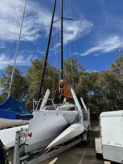 Slide: The Image of 2022 Corsair 880 Sport sailboat on trailer, surrounded by trees under a blue sky. - 22