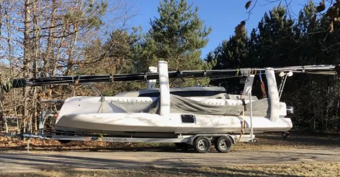 Slide: The Image of 2022 Corsair 880 Sport sailboat on trailer, surrounded by trees, under clear blue sky. - 23
