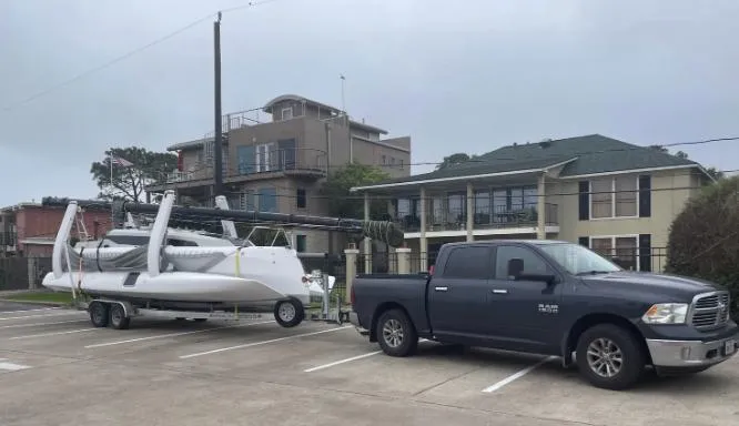 Slide: The Image of 2022 Corsair 880 Sport sailboat on trailer, parked with a pickup truck in a residential area. - 24