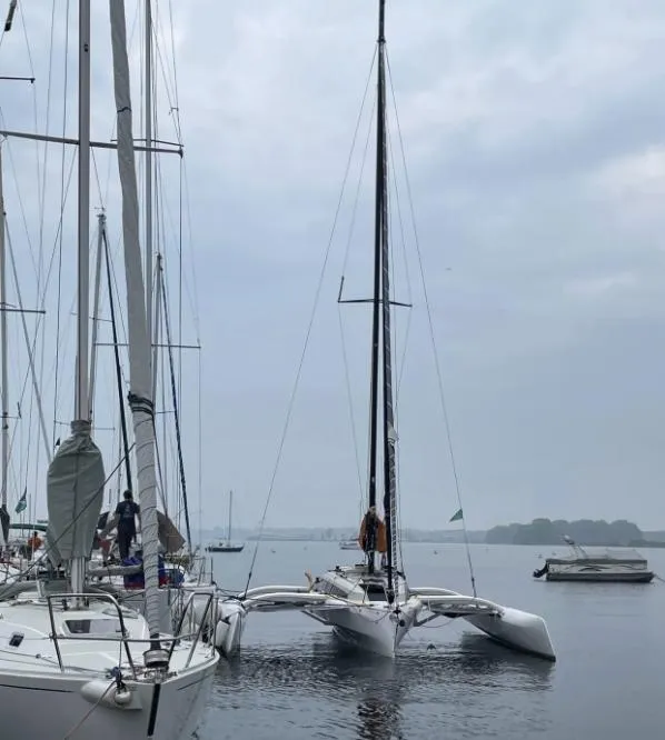 Slide: The Image of 2022 Corsair 880 Sport trimaran docked in a serene marina setting. - 7