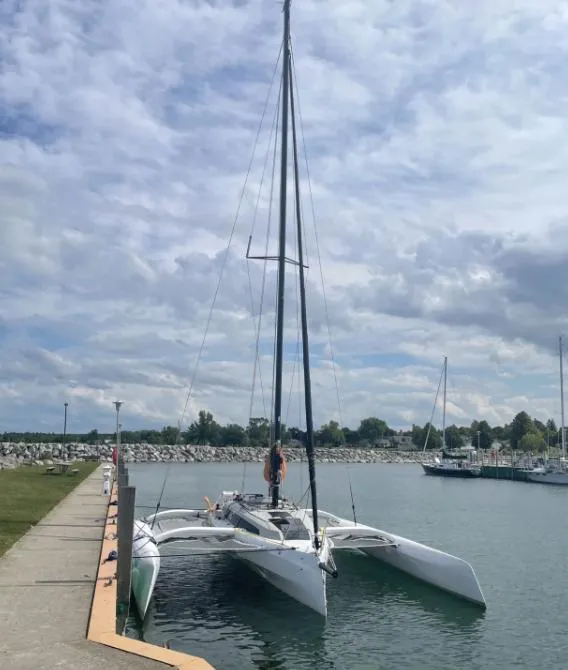 Slide: The Image of 2022 Corsair 880 Sport trimaran docked at a marina under a cloudy sky. - 8