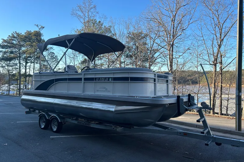 Slide: The Image of 2023 Bennington 23 SSR S pontoon boat on trailer by a lake. - 4