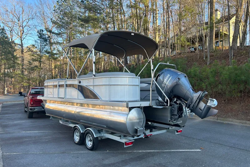 Slide: The Image of 2023 Bennington 23 SSR S pontoon boat on trailer in wooded parking area. - 7