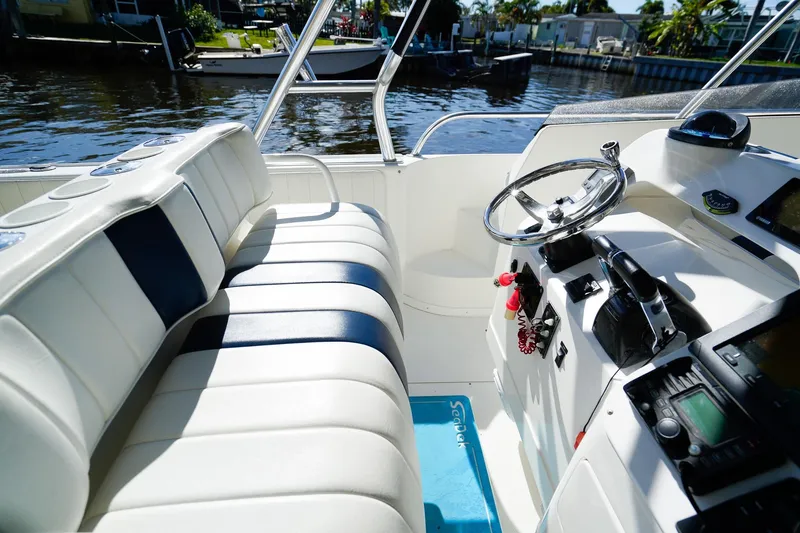 Slide: The Image of 2003 Intrepid 310 Walkaround boat interior with steering wheel and seating, docked by the water. - 12