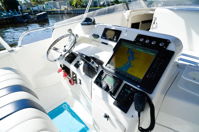 Slide: The Image of 2003 Intrepid 310 Walkaround boat helm with navigation equipment and steering wheel. - 13