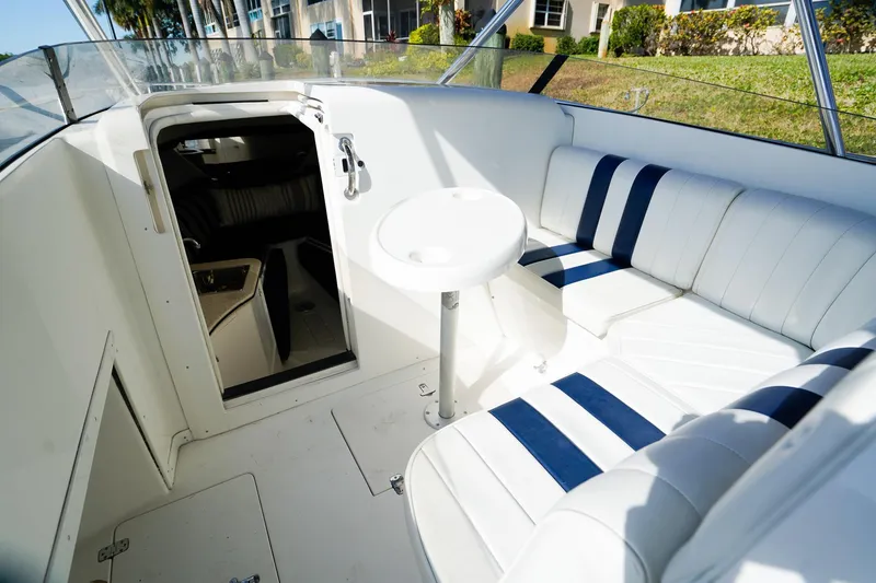Slide: The Image of 2003 Intrepid 310 Walkaround boat interior with white and blue seating and cabin entrance. - 19