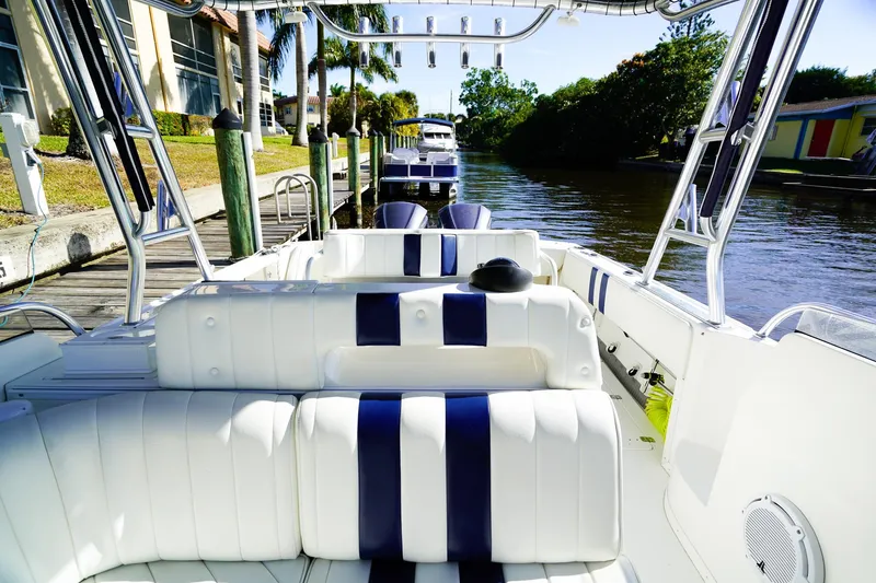 Slide: The Image of 2003 Intrepid 310 Walkaround boat with white and blue seating, docked by a canal. - 20