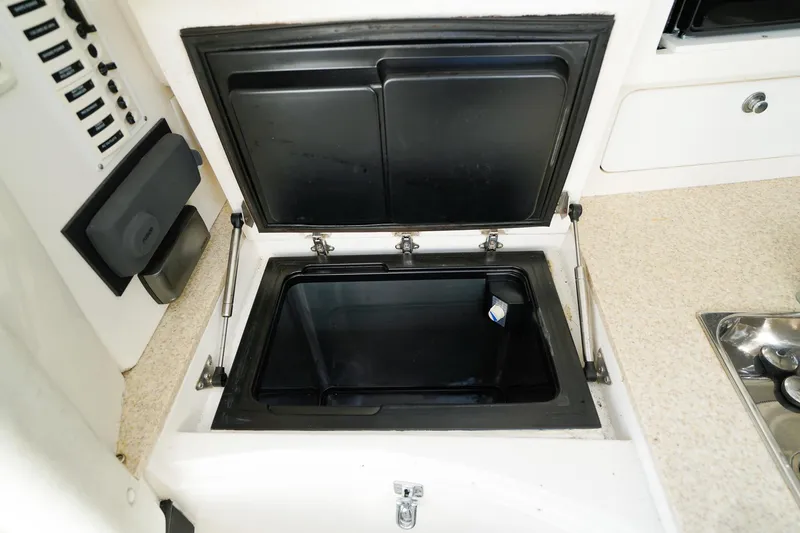 Slide: The Image of 2003 Intrepid 310 Walkaround boat interior storage compartment with open lid. - 23