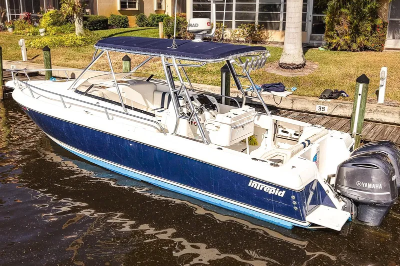 Slide: The Image of 2003 Intrepid 310 Walkaround boat docked with Yamaha engines, featuring a blue and white design. - 3