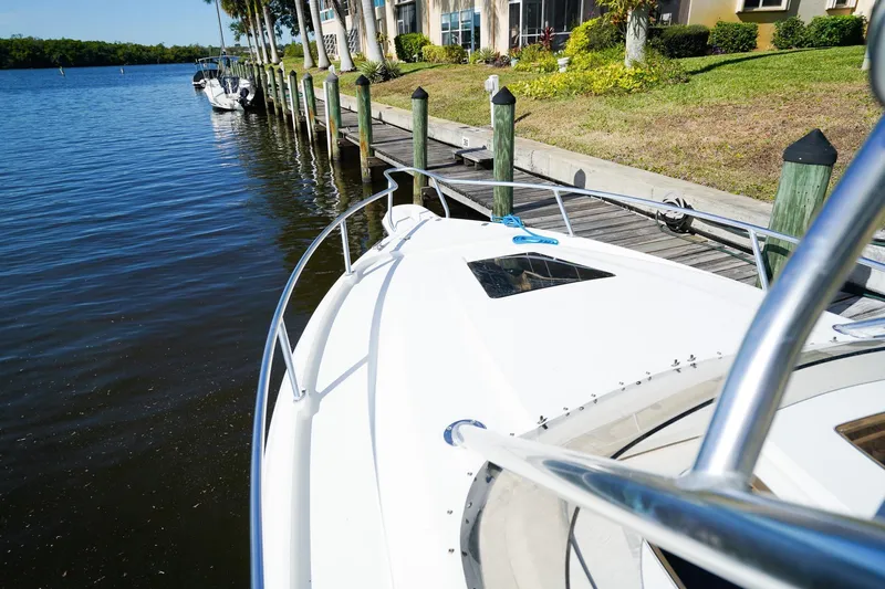 Slide: The Image of 2003 Intrepid 310 Walkaround boat docked by a scenic waterfront. - 31