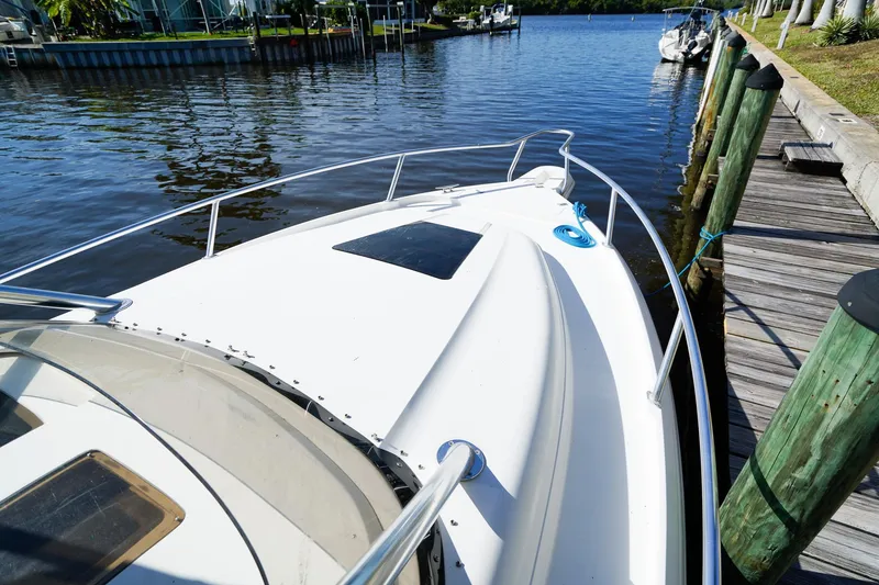 Slide: The Image of 2003 Intrepid 310 Walkaround boat docked by a wooden pier on a sunny day. - 34