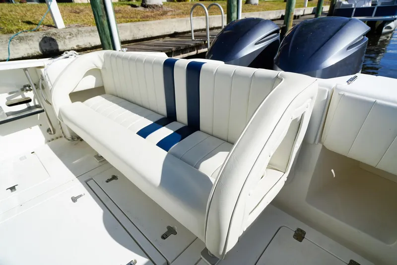 Slide: The Image of 2003 Intrepid 310 Walkaround boat with white and blue seating, docked by the water. - 9