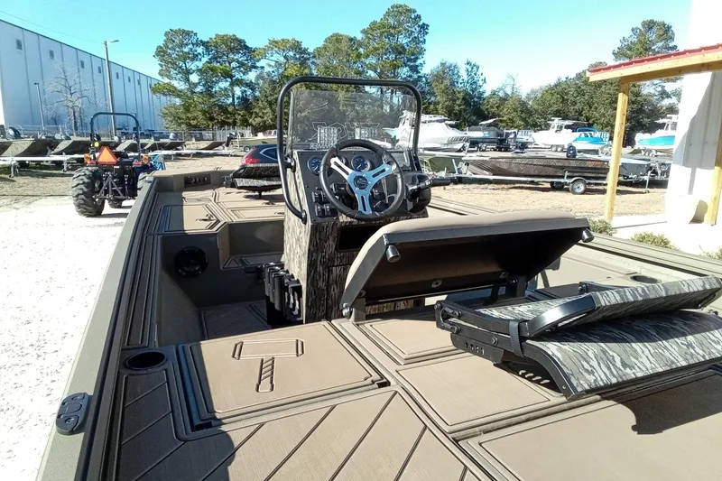 Slide: The Image of 2026 Thor 1900 Lake Hammer boat with camo seats and steering console, parked outdoors. - 12