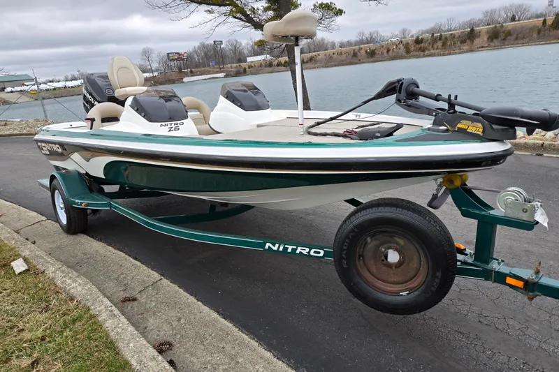 Slide: The Image of 2008 Nitro Z-6 boat on trailer by a lake, featuring dual seats and a trolling motor. - 9
