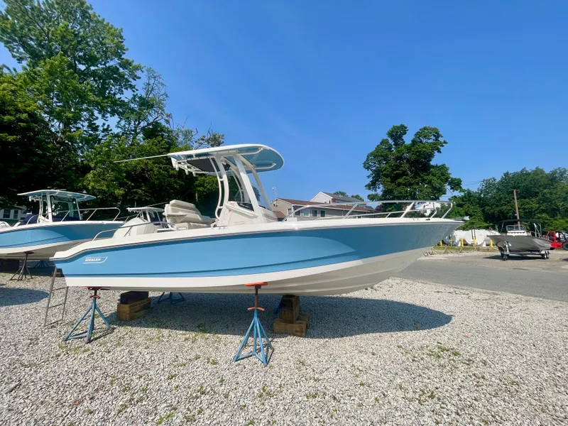 Slide: The Image of A 2026 Boston Whaler 220 Dauntless is on a gravel lot, supported by stands. - 0