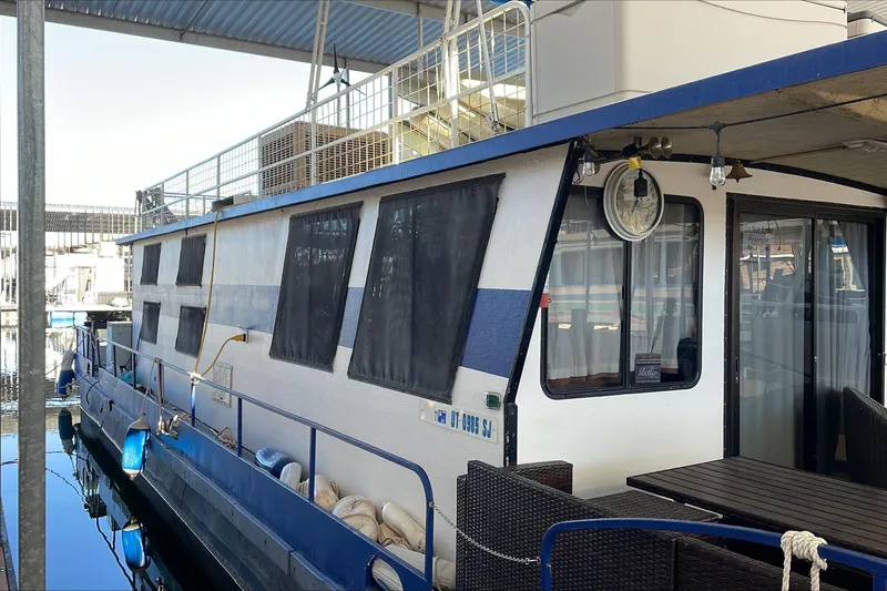 Slide: The Image of 1986 Boatel Hercules houseboat docked, featuring outdoor seating and blue accents. - 3