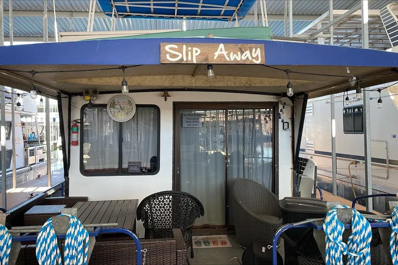 Slide: The Image of Houseboat "Slip Away" docked, featuring outdoor seating, Boatel Hercules 1986 model. - 8