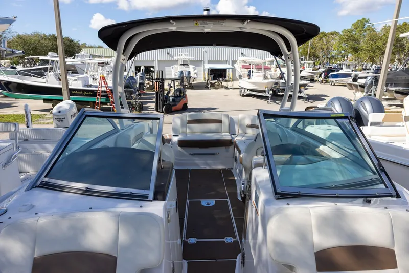 Slide: The Image of 2018 Chaparral 264 Sunesta boat interior with seating and windshield, docked at a marina. - 13