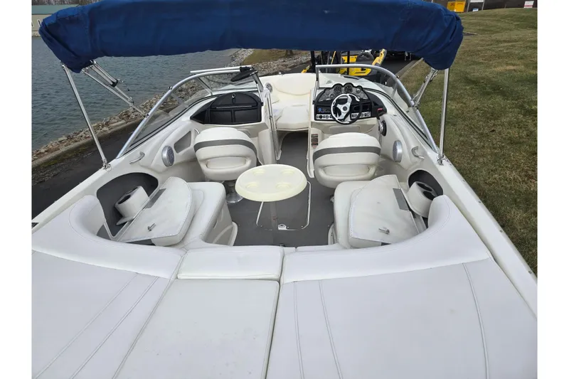 Slide: The Image of 2009 Bayliner 225 boat interior with seating and steering wheel, docked by the water. - 10