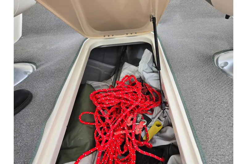 Slide: The Image of Open storage compartment in 2009 Bayliner 225 boat with red rope and gear inside. - 13