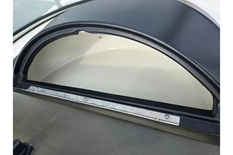 Slide: The Image of 2009 Bayliner 225 boat dashboard detail with black trim and metal hinge. - 16