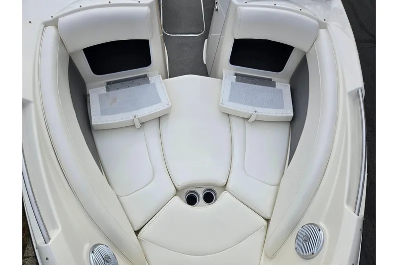 Slide: The Image of 2009 Bayliner 225 boat interior with white cushioned seating and storage compartments. - 19