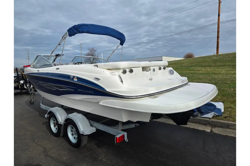 Slide: The Image of 2009 Bayliner 225 boat on trailer, blue and white design, parked outdoors. - 3