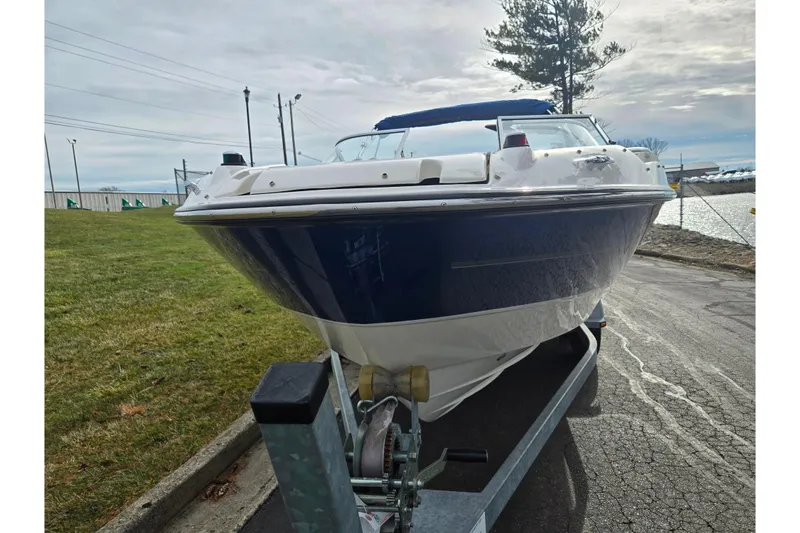 Slide: The Image of 2009 Bayliner 225 boat on trailer, parked near a waterfront. - 6