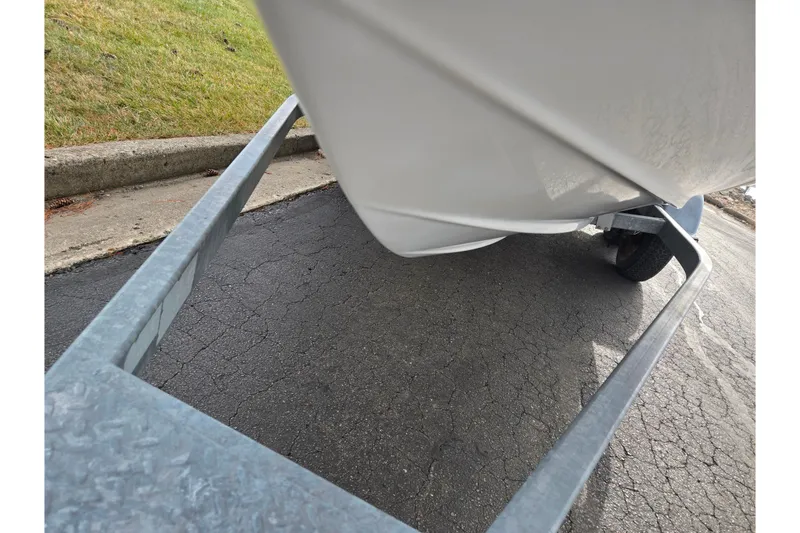 Slide: The Image of 2009 Bayliner 225 boat on trailer, parked on asphalt near grass. - 7