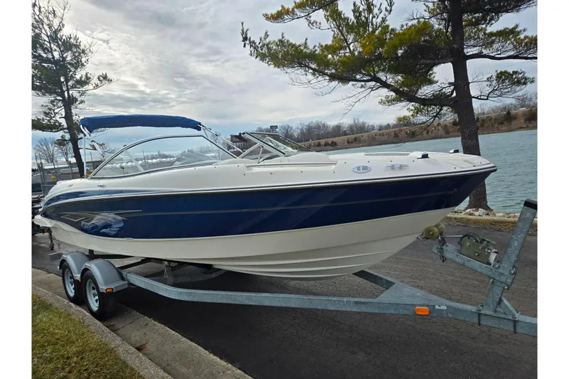 Slide: The Image of 2009 Bayliner 225 boat on trailer by a lakeside, under cloudy sky. - 8