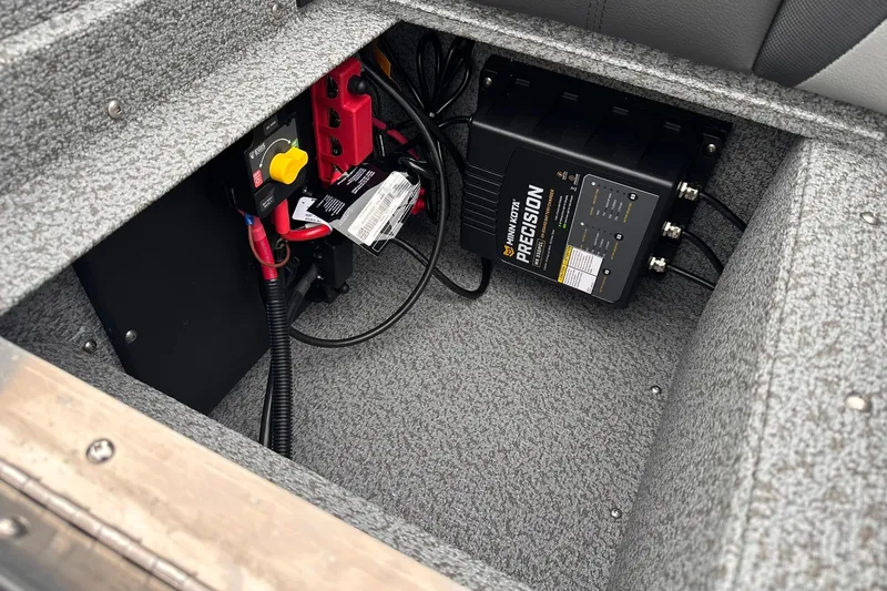 Slide: The Image of 2026 Lund 1775 Impact XS Sport boat battery compartment with Minn Kota Precision charger. - 24
