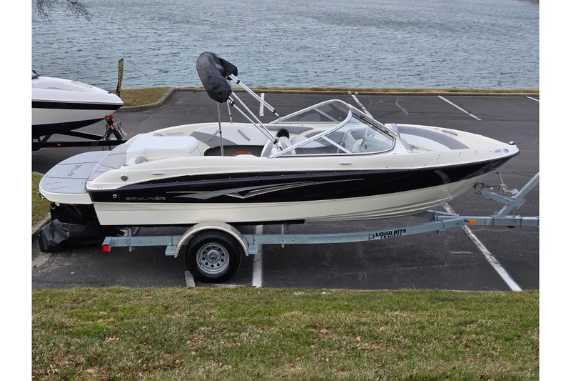 The Image of 2010 Bayliner 185 boat on trailer by a lake, ready for transport. - 0