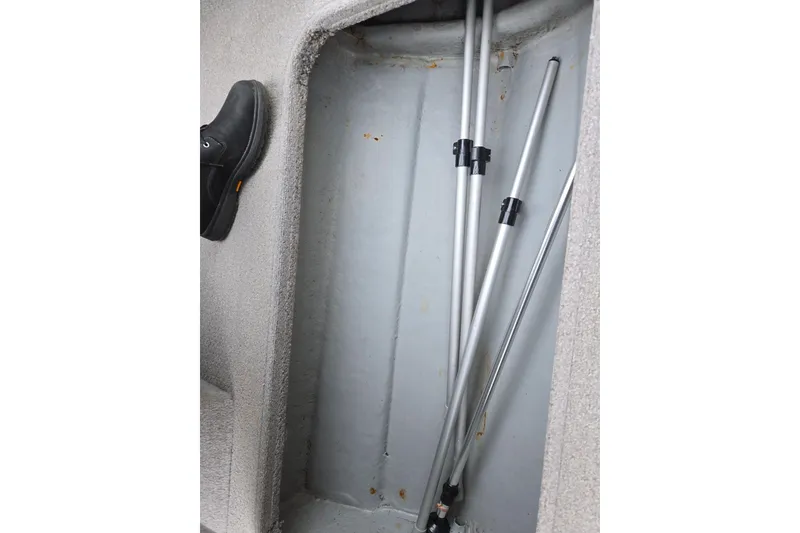 Slide: The Image of Storage compartment in a 2010 Bayliner 185 boat with metal poles and a shoe. - 13