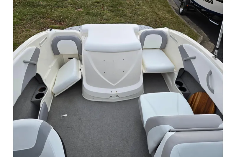 Slide: The Image of 2010 Bayliner 185 boat interior with white and gray seating, cup holders, and carpeted floor. - 21