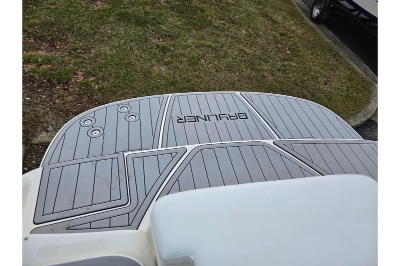 Slide: The Image of 2010 Bayliner 185 boat swim platform with gray decking, parked on grass. - 23