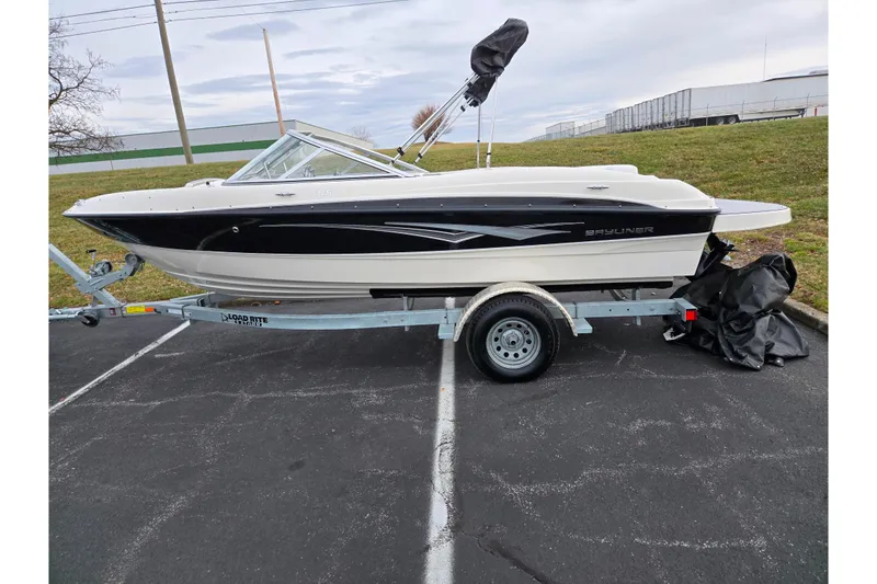 Slide: The Image of 2010 Bayliner 185 boat on trailer, parked outdoors, with black and white design. - 4