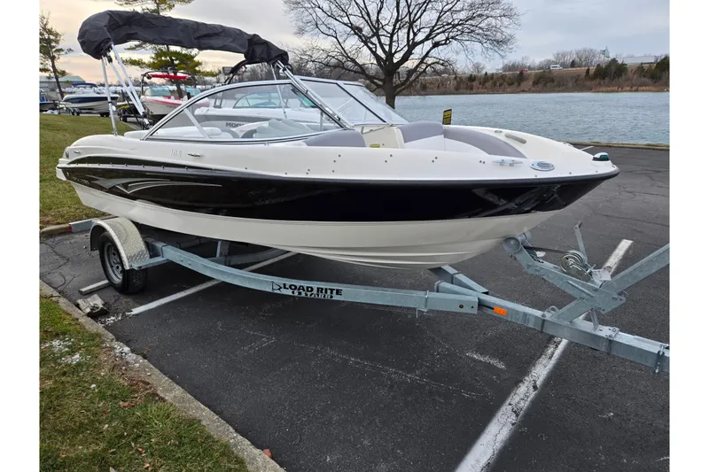 Slide: The Image of 2010 Bayliner 185 boat on trailer by a lakeside parking area. - 8