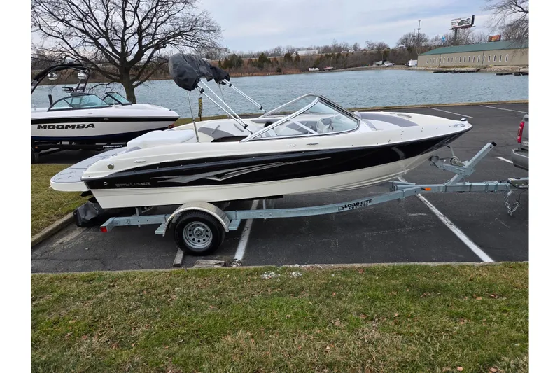 Slide: The Image of 2010 Bayliner 185 boat on trailer near a lake, parked in a lot. - 9
