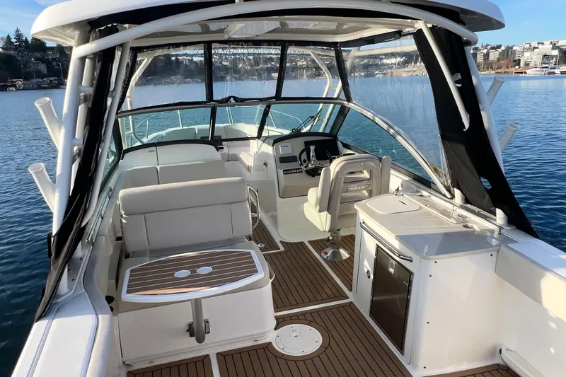Slide: The Image of 2019 Boston Whaler 270 Vantage boat interior with seating and helm, docked on calm water. - 13