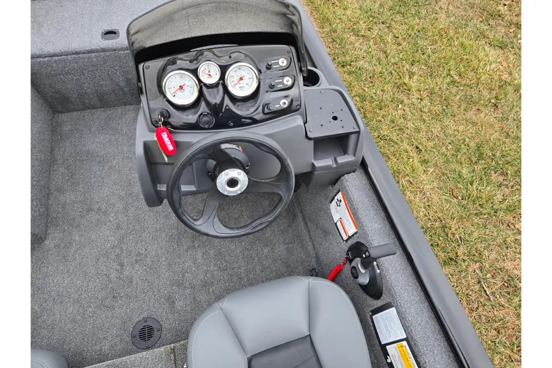 Slide: The Image of 2025 Tracker Pro 170 boat dashboard with steering wheel and gauges, parked on grass. - 12